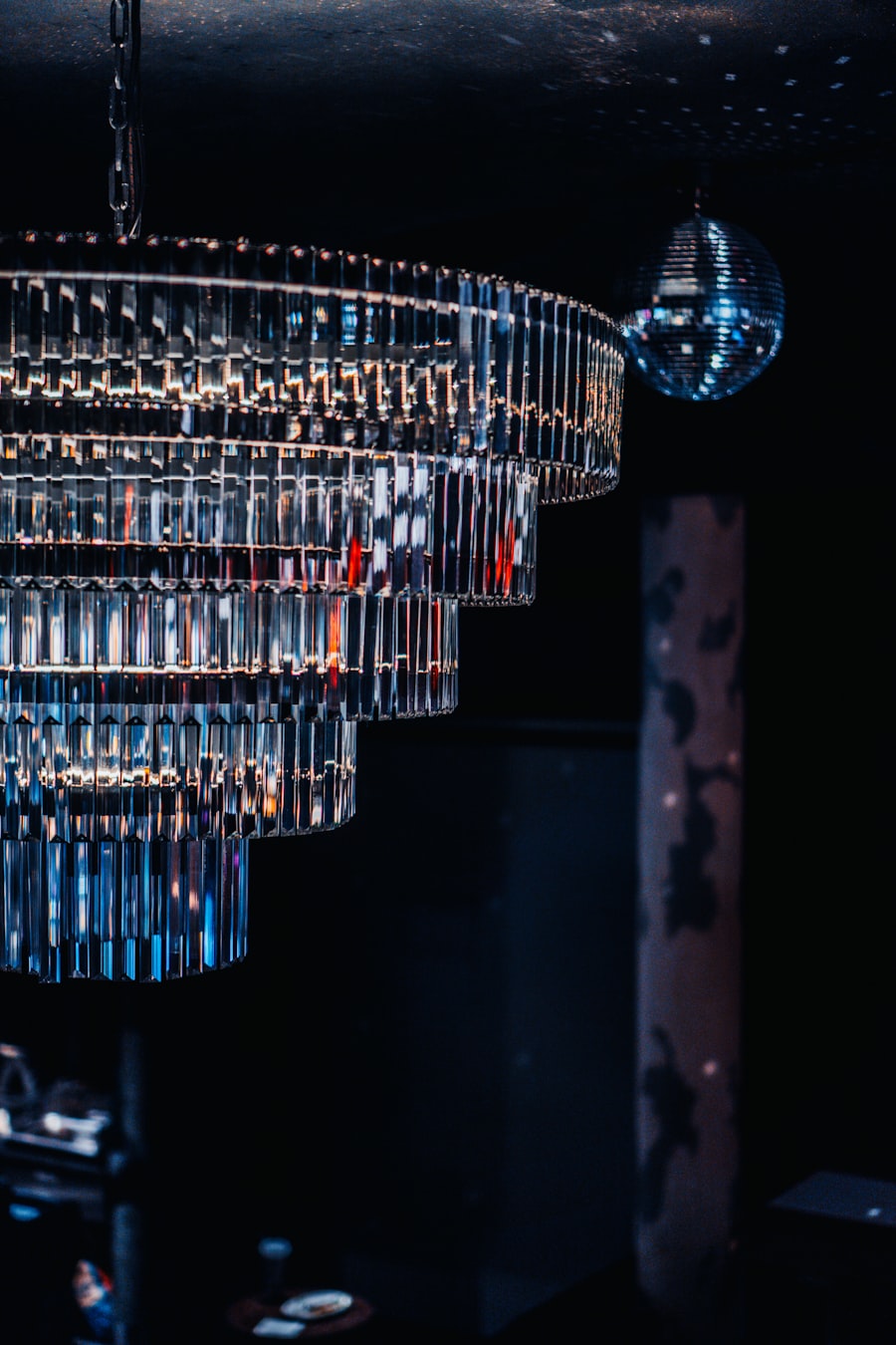 A tiered crystal chandelier and a mirror ball in a dark room